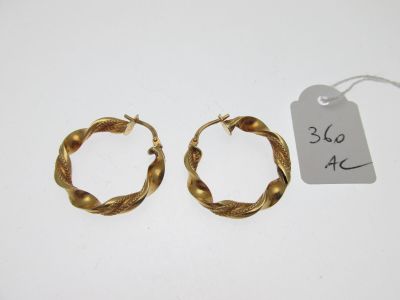 une paire de boucles d'oreilles créoles en or avec son étiquette de prix