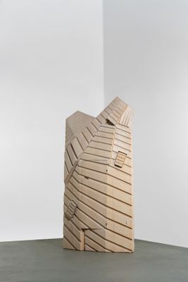 une sculpture en bois posée sur une table, avec un mur blanc en arrière-plan