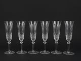 six crystal wine glasses lined up against a black background