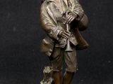 bronze figurine of a man in a hat and coat holding a rifle