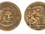 a close up of a coin with a picture of a man playing a piano