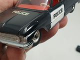 someone is holding a toy police car in their hand