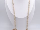 un mannequin blanc portant un collier, posé sur un socle en bois
