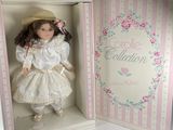 doll in a white box with pink stripes and a pink bow