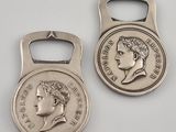 two silver coin shaped bottle openers with a picture of a woman ' s face on them