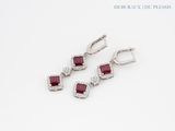 trois paires de boucles d'oreilles en rubis et diamants posées sur un fond blanc