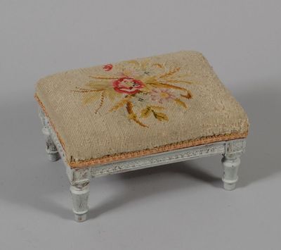 un petit repose-pieds orné d'un motif brodé