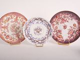 three plates with floral designs on them sitting on a white surface