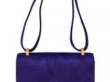 a purple sued handbag with a gold metal handle