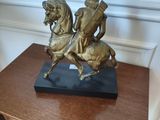 a bronze statue of a man riding a horse on a table