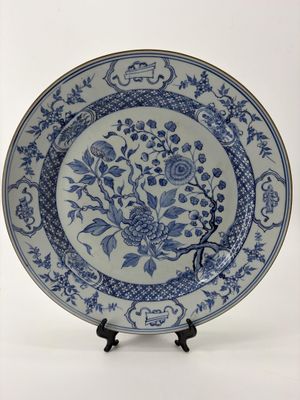 assiette bleue et blanche ornée de fleurs et d'oiseaux, posée sur un socle