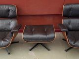 deux fauteuils en cuir noir et un petit pouf devant un mur rouge