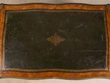 an old wooden table with a black leather top and gold trimming