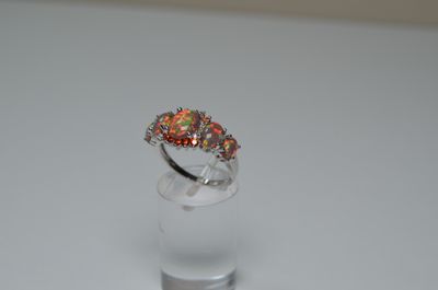 sterling silver ring with multi colored stones on top of a clear glass