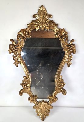 un miroir au cadre doré ouvragé accroché à un mur blanc