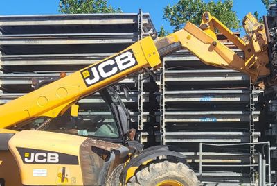 une grosse machine jaune garée devant un tas de palettes