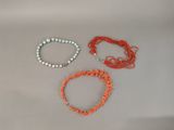 three bracelets of different colors and sizes on a white surface