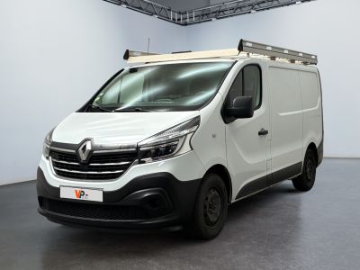 La camionnette blanche est garée dans une grande pièce au sol noir.