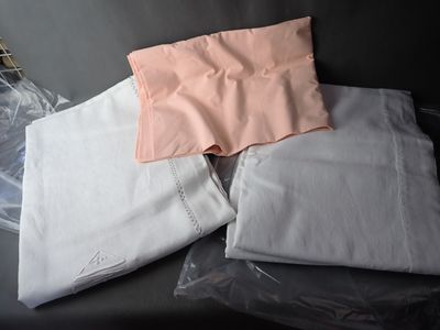 a pile of folded white and pink shirts on a black couch