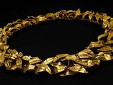 a close up of a gold necklace on a black background