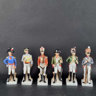 cinq figurines représentant des hommes en uniforme et coiffés de chapeaux sont alignées en rang
