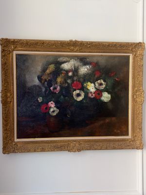 un tableau accroché au mur d'une pièce où se trouve un vase de fleurs