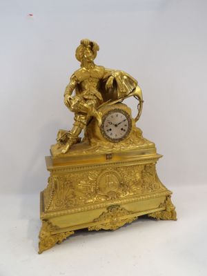 a gold clock with a man sitting on top of it