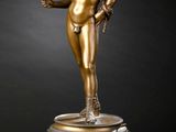 une statue en bronze représentant un homme tenant une balle, posée sur un socle en marbre