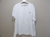 white t - shirt hanging on a hanger against a wall