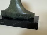 a green sculpture of a shoe on a marble base