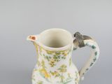 a small pitcher with a bird on it on a table