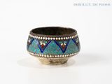 an old silver bowl with a blue and red design on it