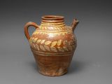 un vieux vase marron et blanc muni d'une anse, sur un fond gris