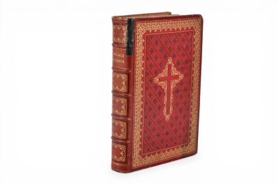 un vieux livre rouge orné d'une croix, posé sur une surface blanche