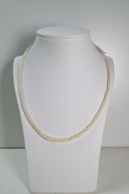 collier composé de perles blanches et dorées, présenté sur un mannequin blanc