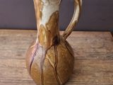 a brown and white vase sitting on a wooden table