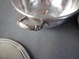 a silver bowl sitting on a table next to a plate