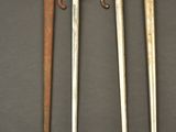 three old swords are displayed on a table with a gray background