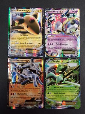 Quatre cartes Pokémon différentes sont représentées sur une surface noire.