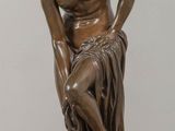 bronze statue of a man sitting on a rock with his hands on his knees