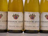 four bottles of white wine are lined up on a table