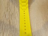 the watch is yellow and has a white logo on it
