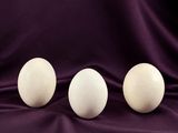three white eggs sitting on top of a purple cloth