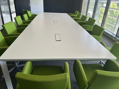 de nombreuses chaises vertes disposées autour d'une table blanche dans une salle de réunion