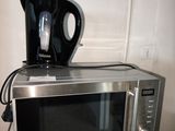 une cafetière posée sur un micro-ondes, lui-même posé sur un plan de travail