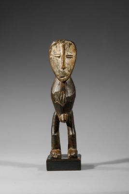 une statue en bois représentant un homme debout sur un socle noir