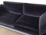 a black velvet couch with studded legs and a black cushion