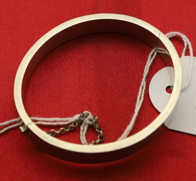 un bracelet auquel est attachée une étiquette, posé sur un fond rouge