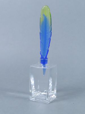 une photo d'une plume bleue et verte dans un vase en verre