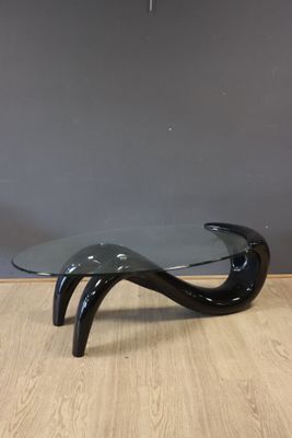 a black glass coffee table with curved legs and a curved glass top